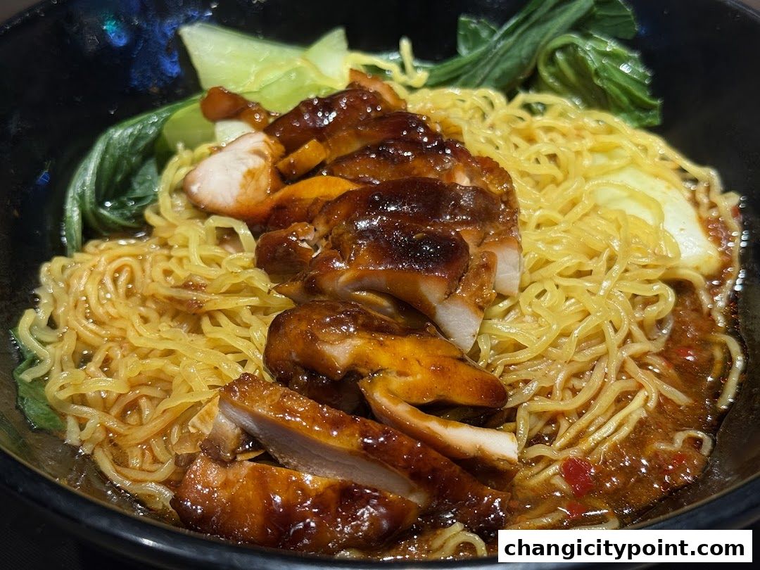 A close-up of a delicious bowl of noodles topped with succulent roasted meat and fresh greens.