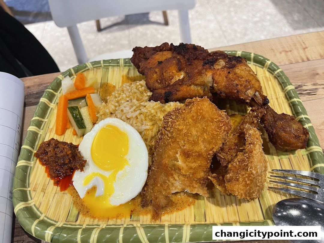 A plate of nasi lemak with fried chicken, sunny-side-up egg, sambal, and pickled vegetables.