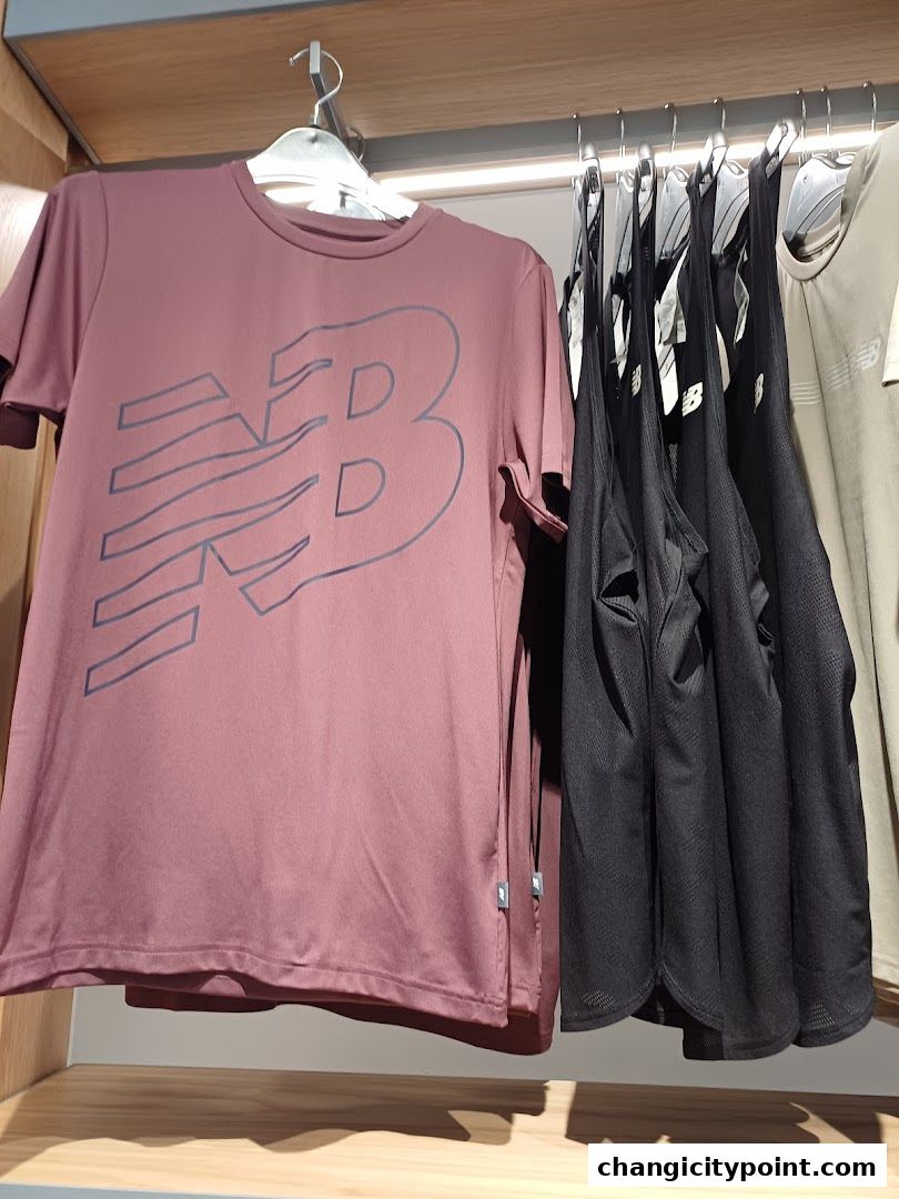 New Balance t-shirts and tank tops displayed on hangers in a retail store.