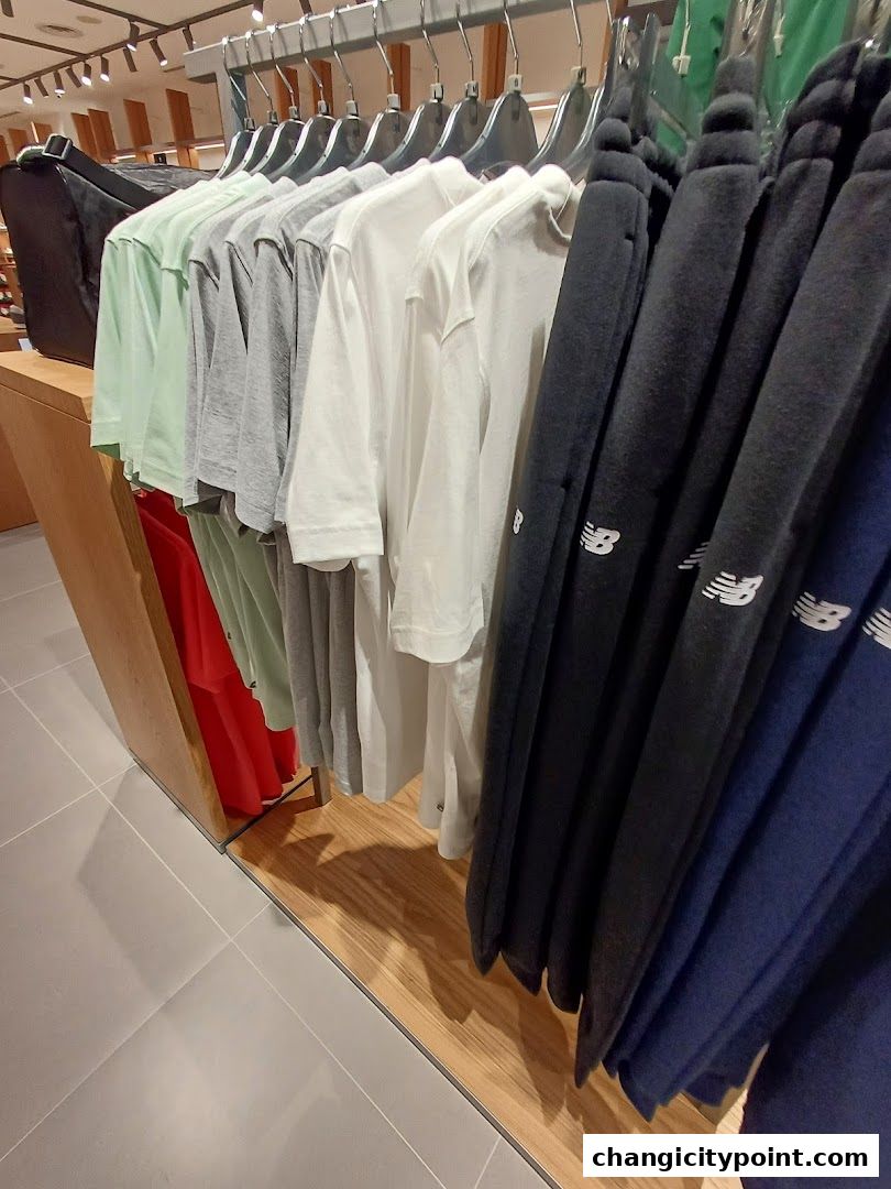 New Balance apparel displayed on hangers inside a retail store.
