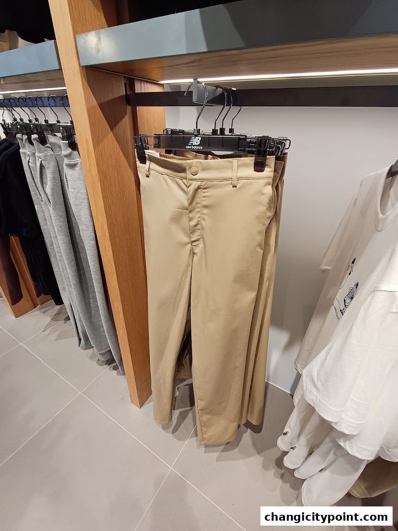 New Balance store interior showcasing beige trousers and white t-shirts on display.