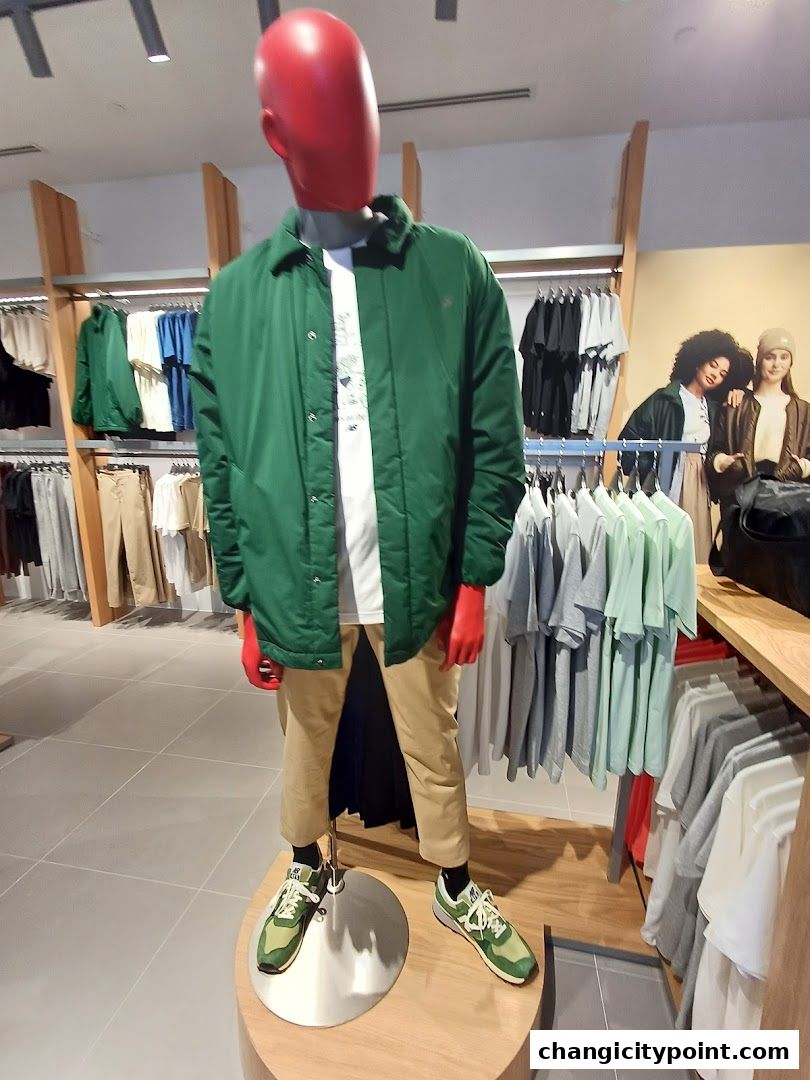 Mannequin wearing a green jacket, white t-shirt, and tan pants, showcasing New Balance apparel.