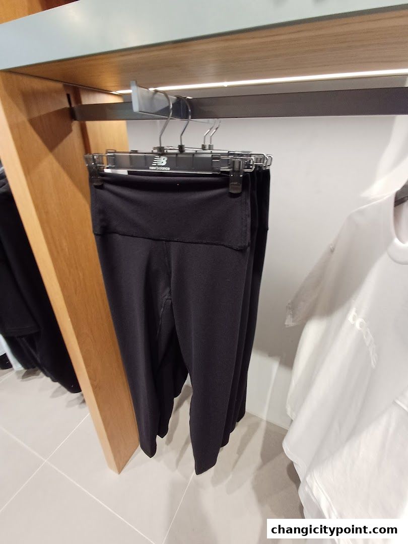 Black athletic leggings and white t-shirts displayed on hangers in a retail store.