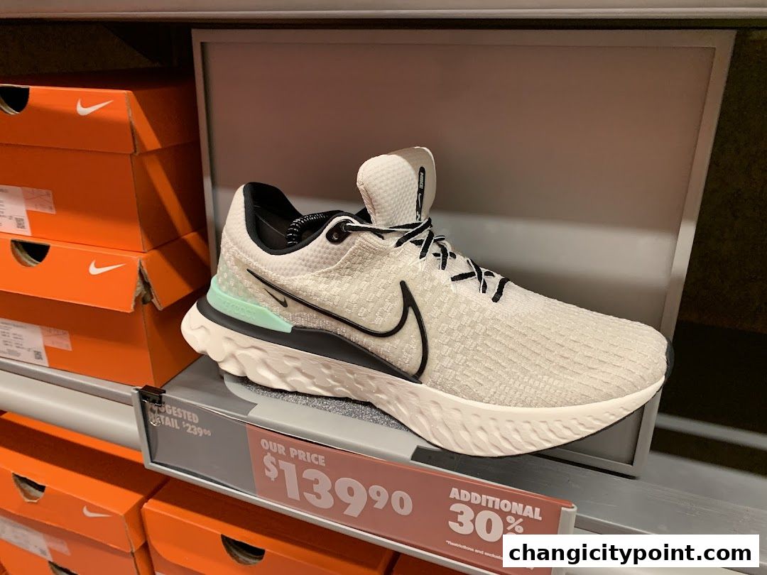 A Nike running shoe displayed with its box and a price tag showing a discount.
