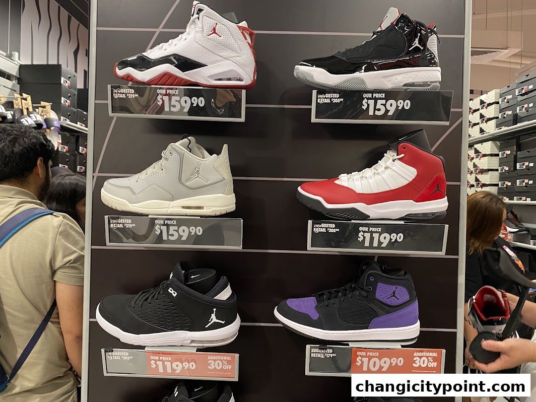 Display of Nike Air Jordan sneakers with prices and discounts at a Nike Factory Store.
