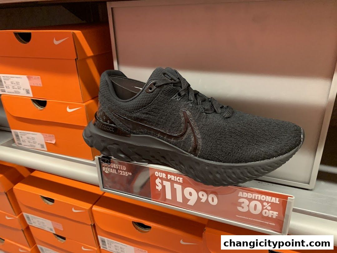 A black Nike running shoe displayed with price tags and stacked shoe boxes.