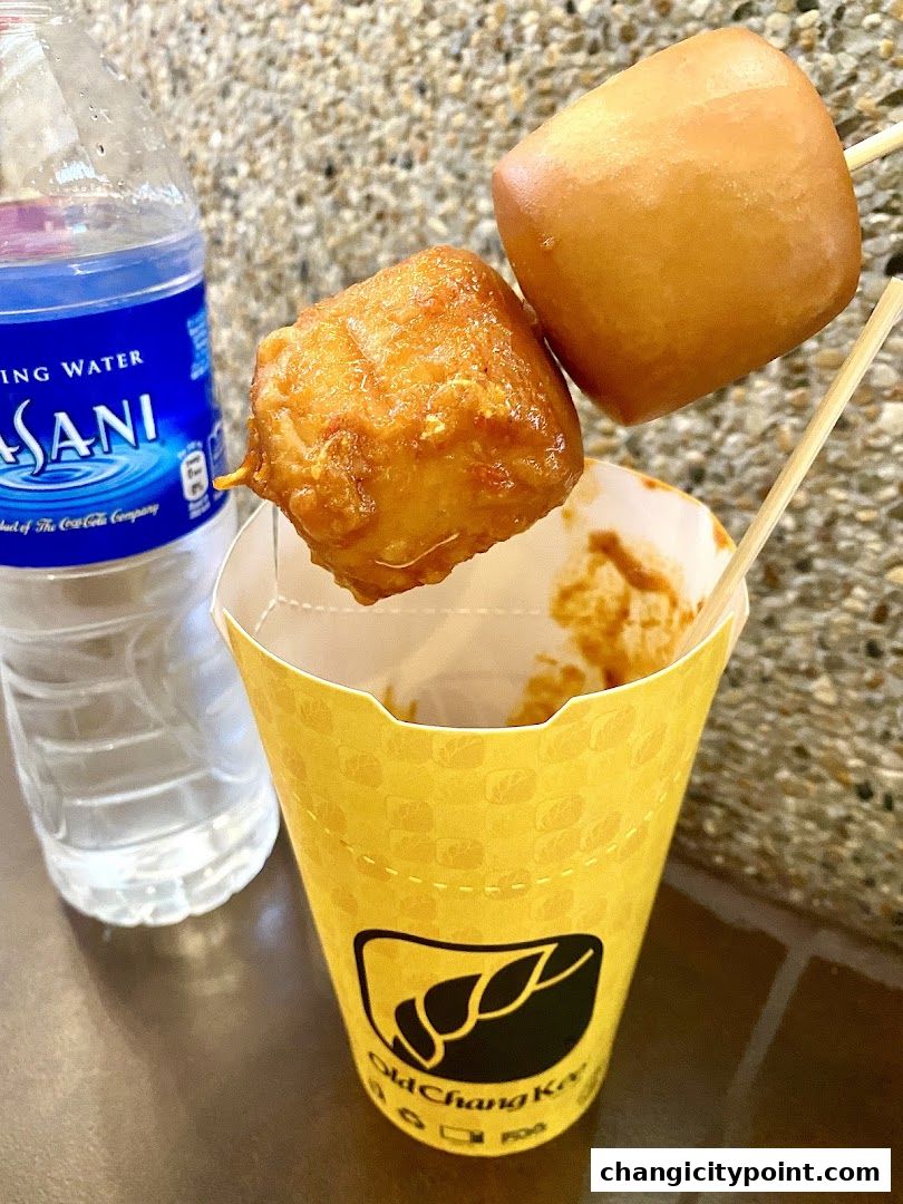 Close-up of Old Chang Kee snacks on skewers with a bottle of water.