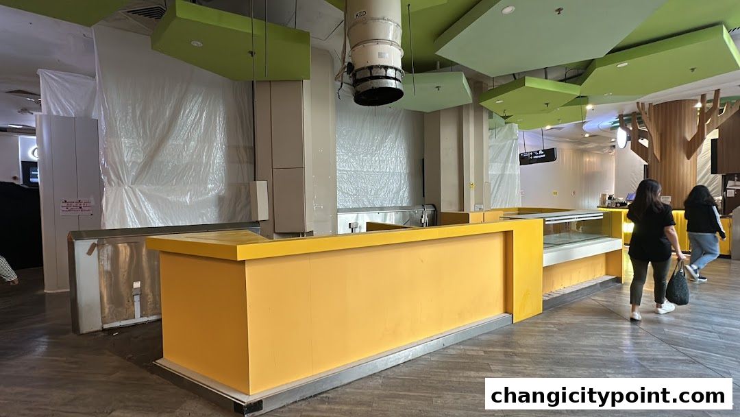 A bright yellow counter and display case in a shop with plastic sheeting on the walls.