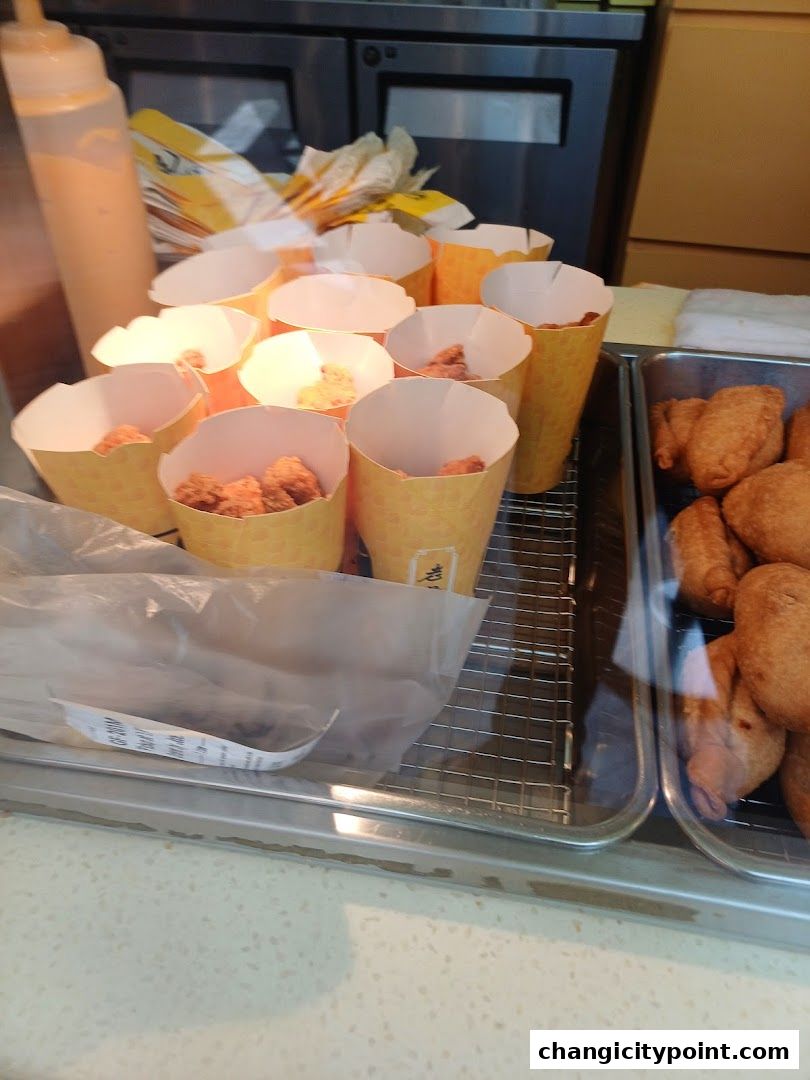 A display of freshly fried snacks in paper cones and a tray at Old Chang Kee.