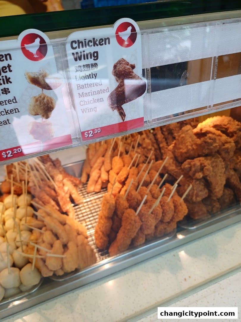 A display of various fried snacks, including chicken wings and meatballs, with prices shown.