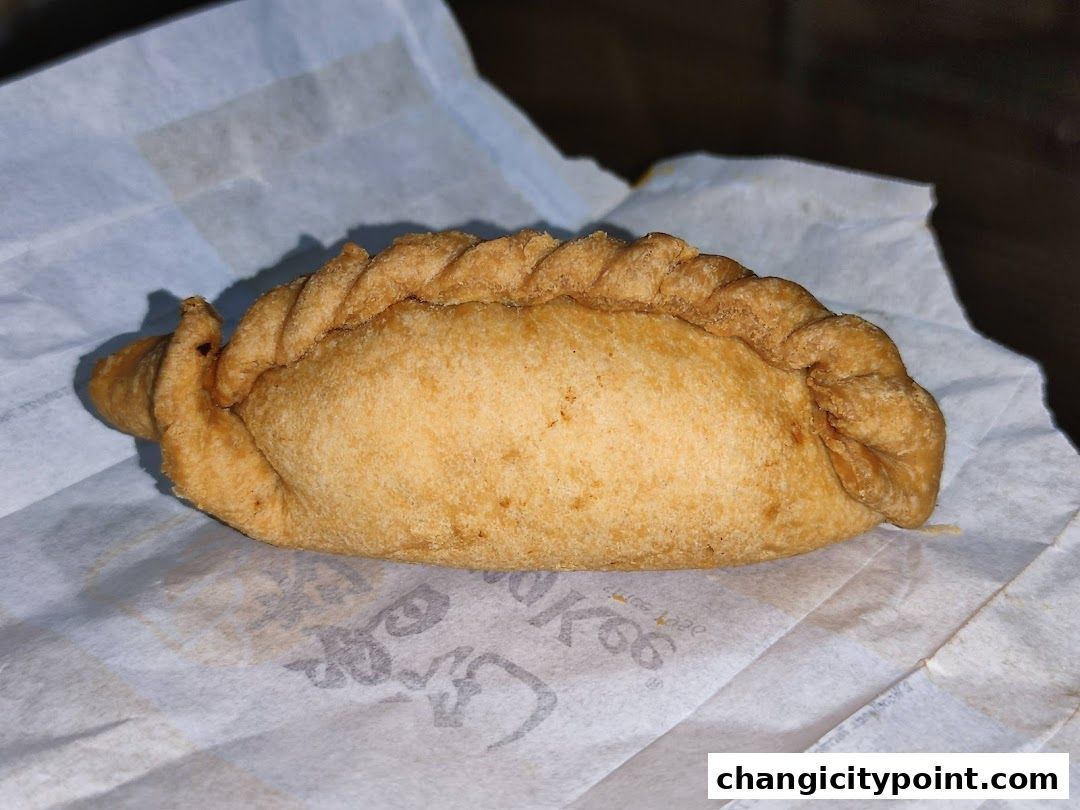 A close-up of a golden-brown, savory pastry on white paper with the Old Chang Kee logo.