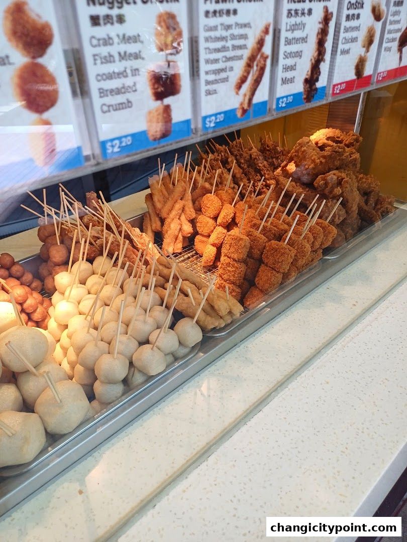 A display of various fried snacks on skewers with their names and prices.