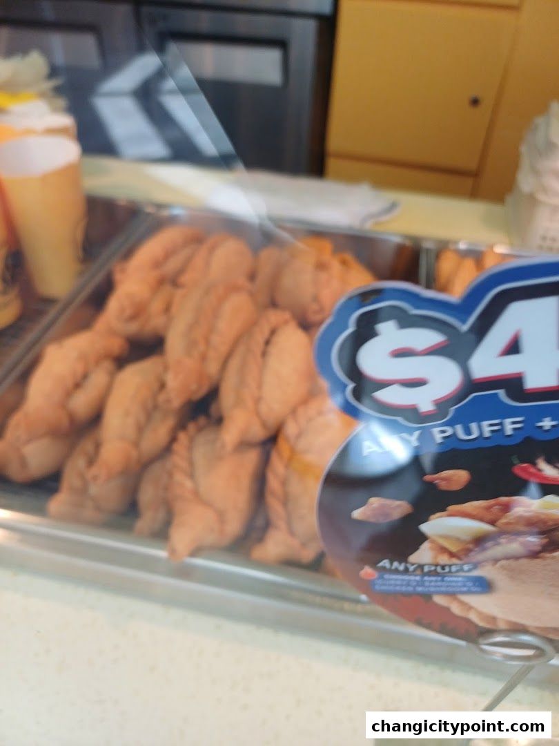 A display of freshly baked pastries at Old Chang Kee, with a promotional sign.