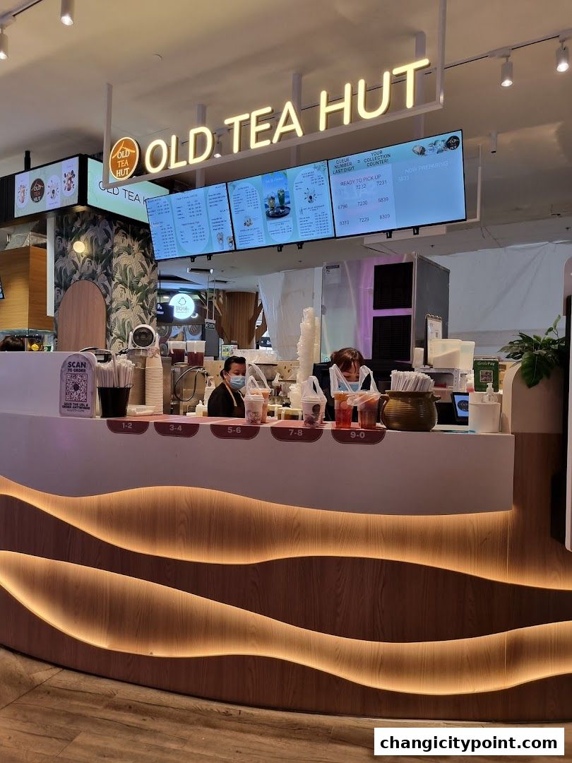 Old Tea Hut shop counter with digital menu screens and staff serving drinks.