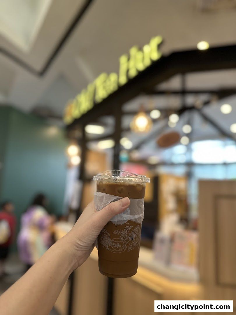 A hand holds a refreshing iced coffee from Old Tea Hut.