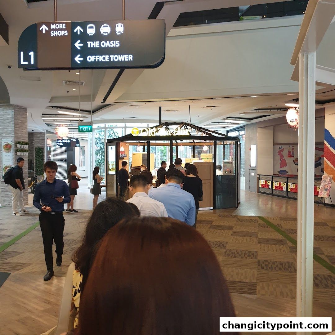 A queue of people waiting outside the Old Tea Hut shop in a mall.