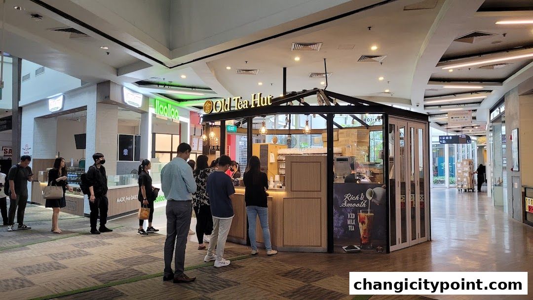 People queuing at the Old Tea Hut shop in a mall, with a sign advertising iced milk tea.