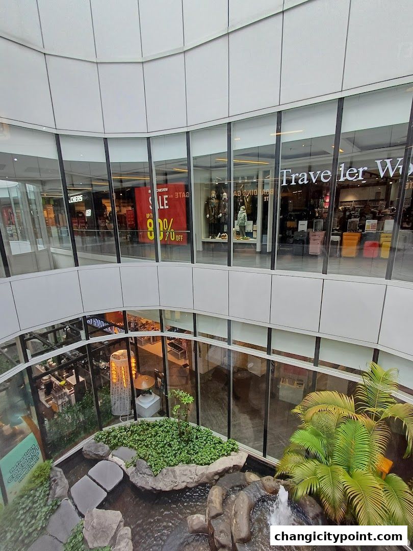 Interior view of a shopping mall with shops and a decorative water feature.