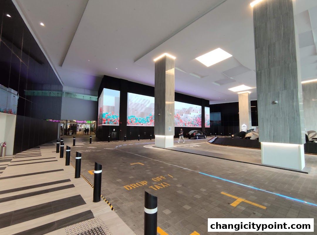Modern entrance with large digital screens and a drop-off area.
