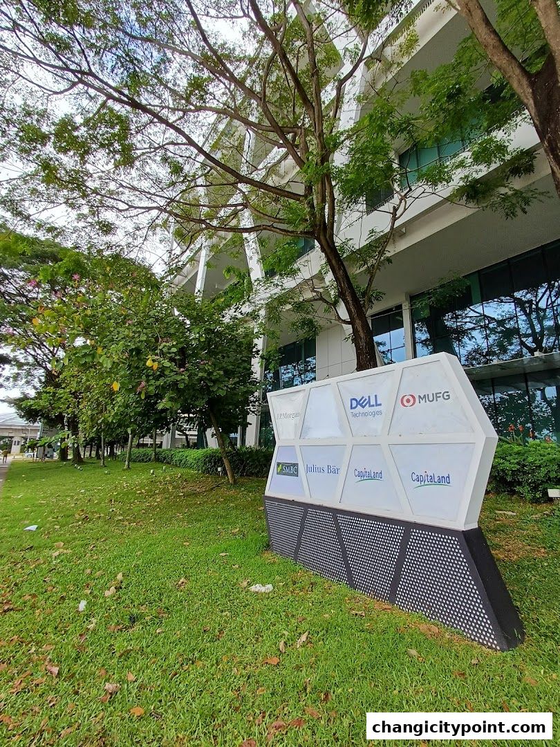 A sign with company logos in front of a modern building with trees.