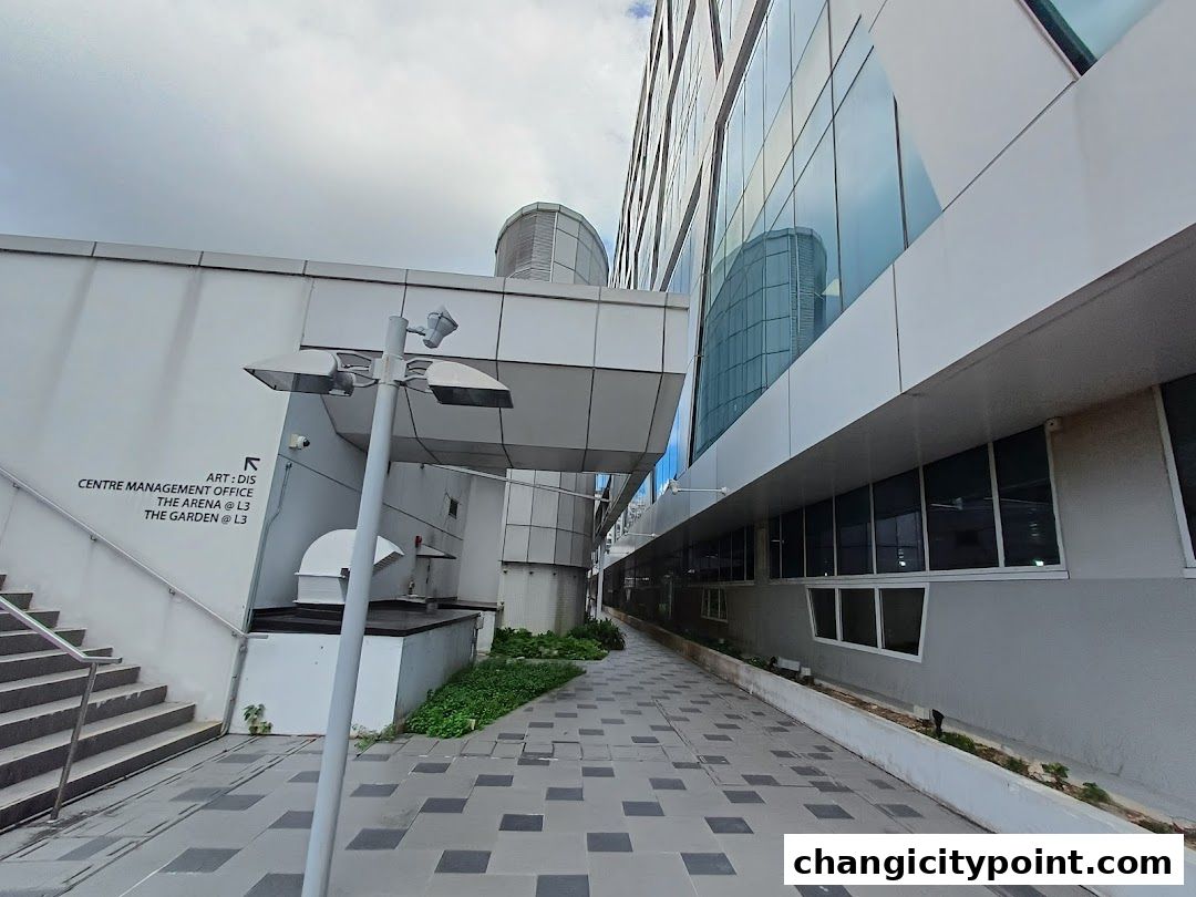 A walkway between modern buildings with signage indicating directions.