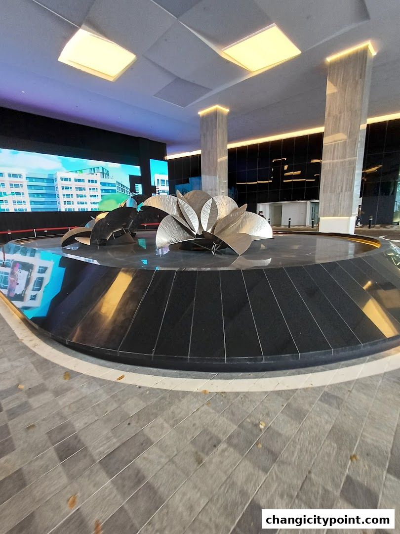 Modern lobby with a large digital screen, sculpture, and marble columns.