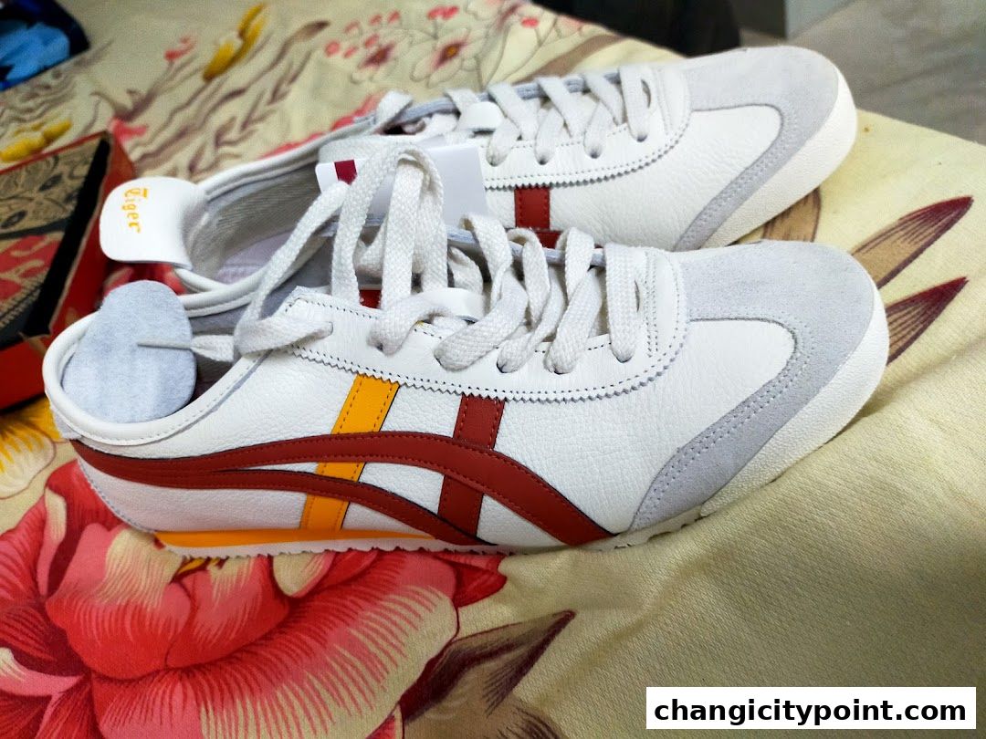 A pair of white Onitsuka Tiger sneakers with red and yellow stripes.