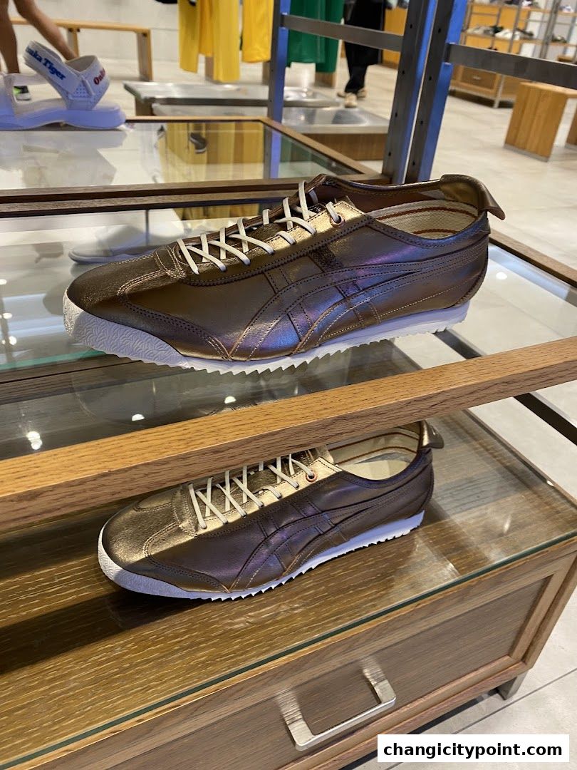 Onitsuka Tiger sneakers displayed in a retail store on wooden shelves.