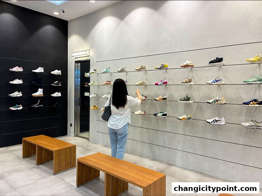 A woman browses a wide selection of Onitsuka Tiger sneakers displayed on shelves.