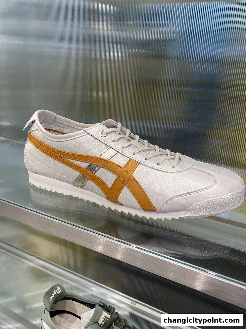 A close-up of a white Onitsuka Tiger sneaker with tan stripes on display.