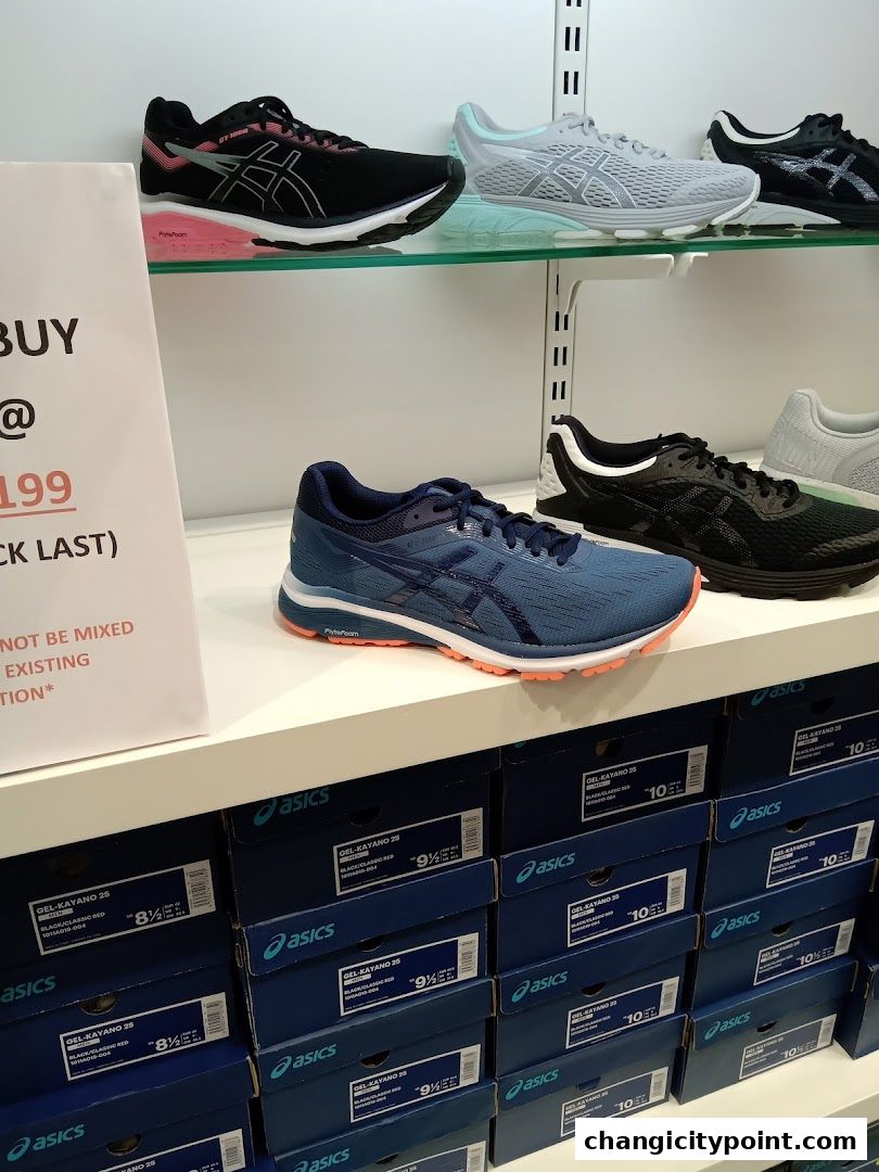 Display of Asics running shoes and their boxes in a retail store.