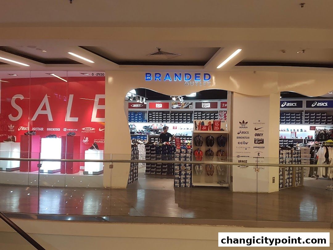 Branded Outlet store entrance with a large SALE sign and displays of shoes and apparel.