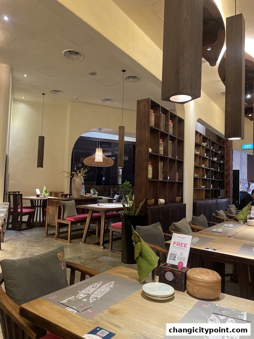 Interior of Paper Rice restaurant with wooden tables, chairs, and shelves.