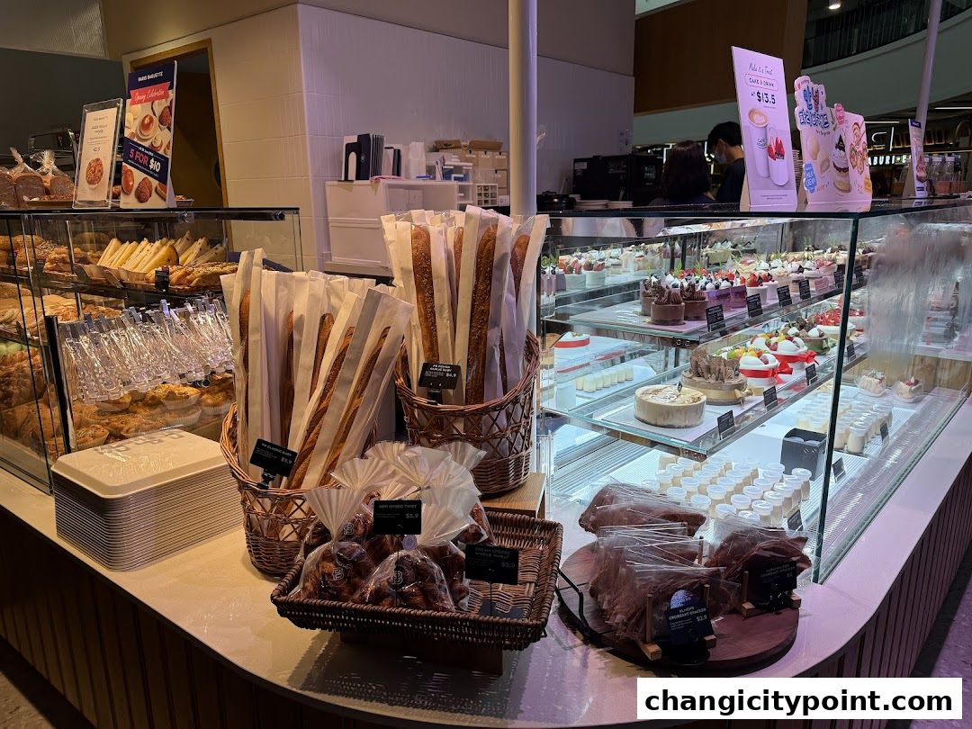 A display of freshly baked bread, pastries, and cakes at Paris Baguette.