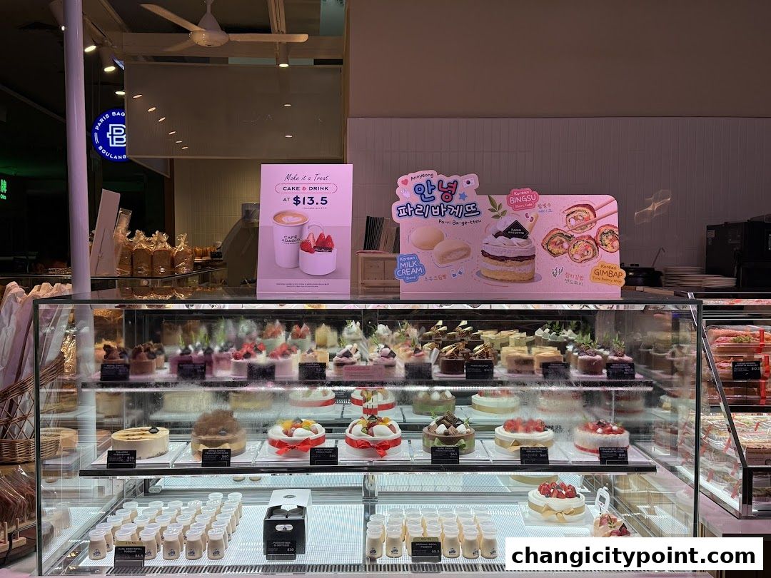 A display case filled with various cakes and desserts at Paris Baguette.