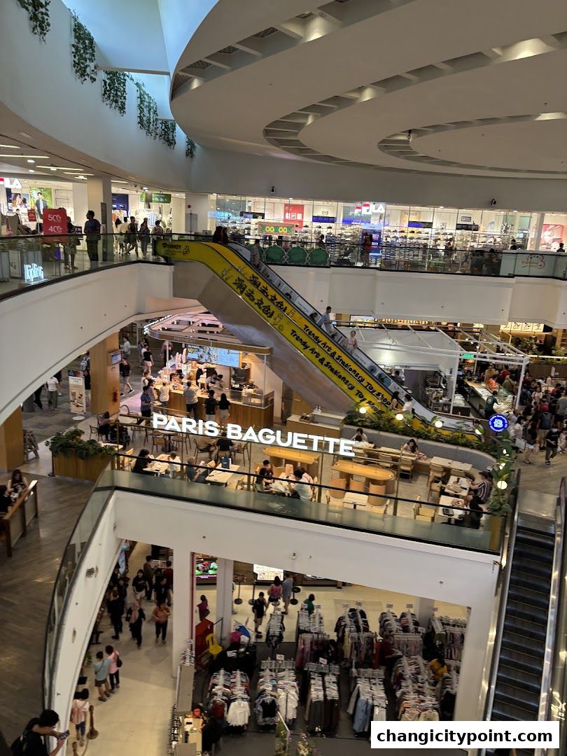 A view of Paris Baguette and other shops in a busy shopping mall.