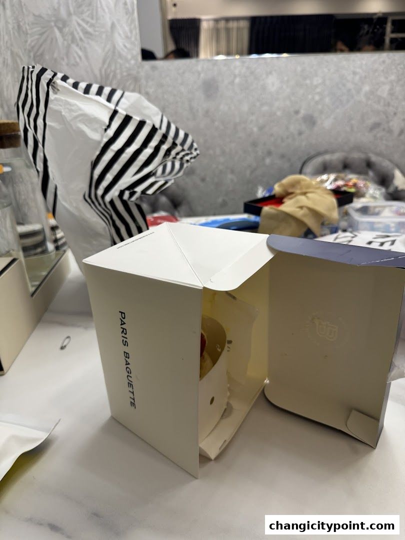 A Paris Baguette cake box is open, revealing a small cake inside.