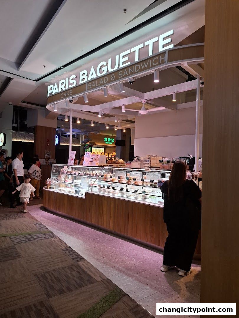 Paris Baguette shop front with display cases filled with cakes and pastries.