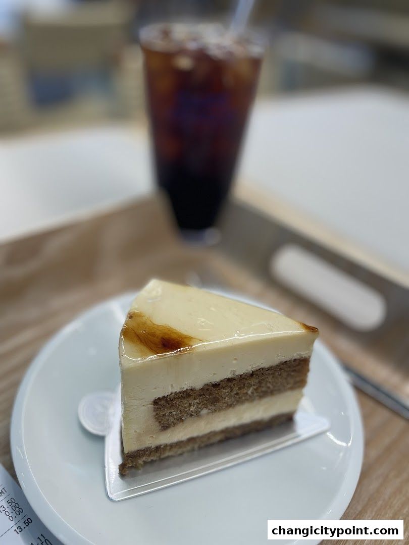A slice of layered cake with a caramel glaze and a glass of iced coffee.