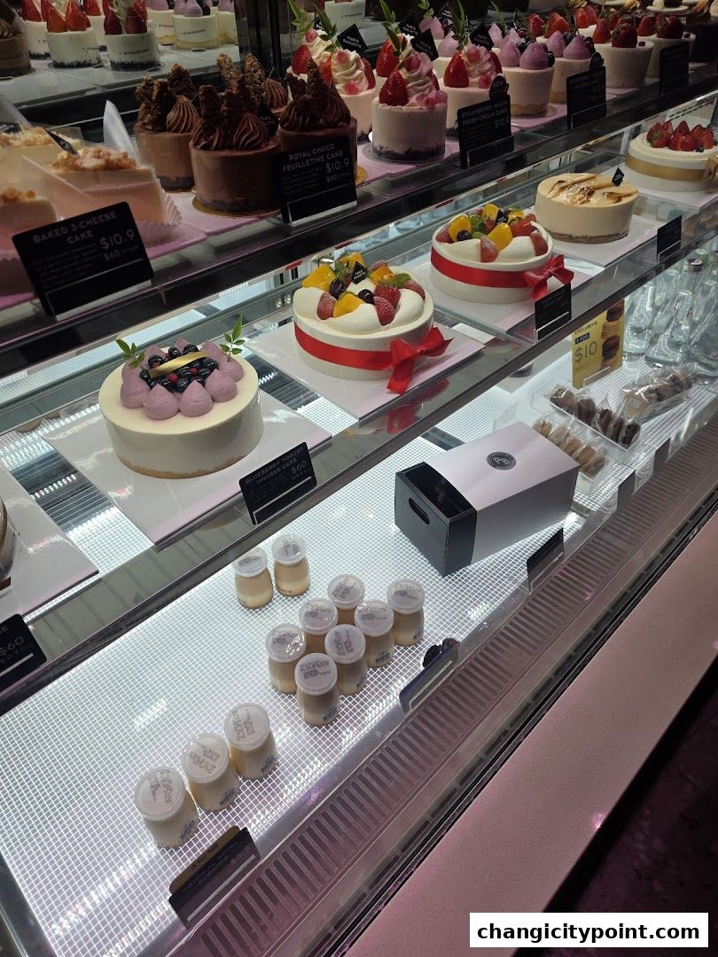 A display case filled with various cakes, pastries, and puddings at Paris Baguette.