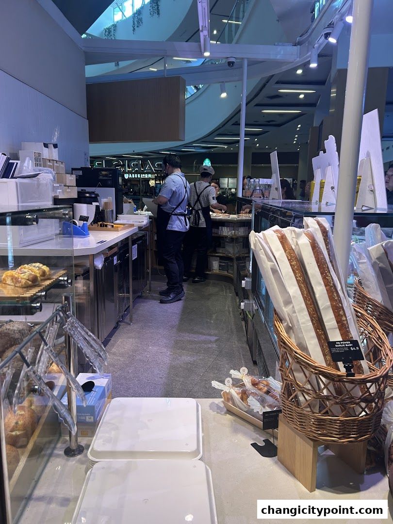 Interior view of a Paris Baguette bakery with staff serving customers and baked goods on display.