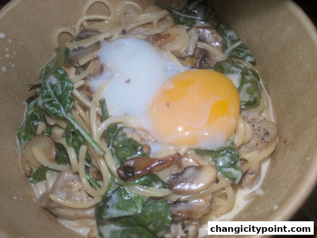 A close-up of a creamy pasta dish with spinach, mushrooms, and a runny egg yolk.