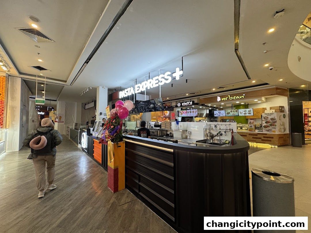 Pasta Express and Mr. Bean food stalls in a mall with a customer walking by.