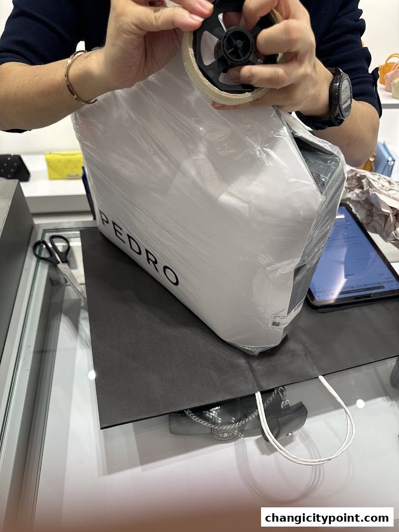 A person is taping a white box with the PEDRO logo, ready for packaging.