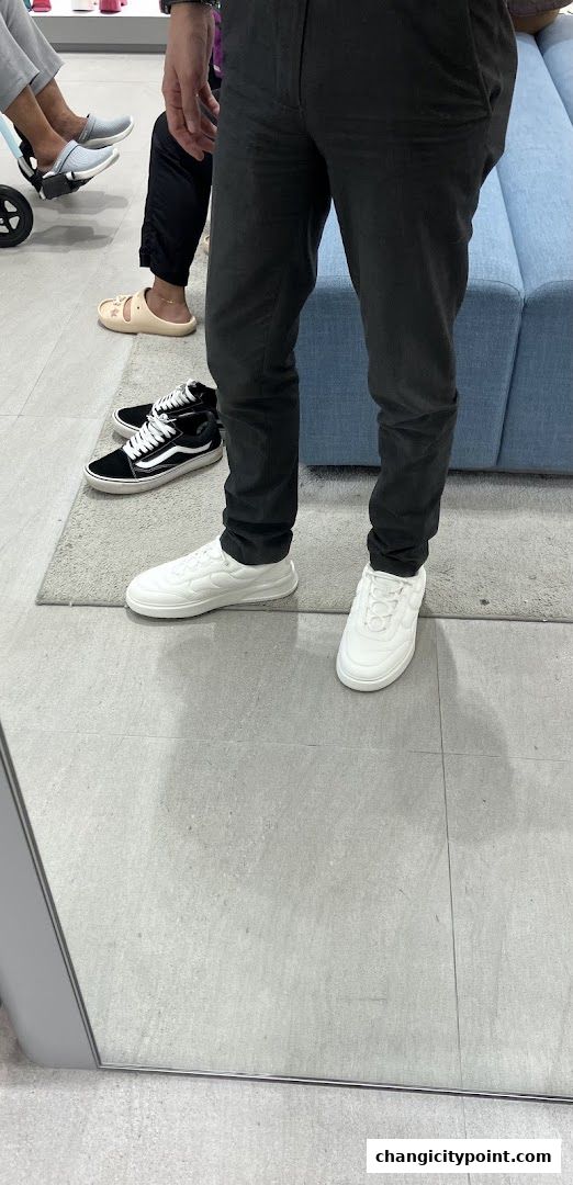 People trying on shoes inside a PEDRO store, showcasing footwear options.