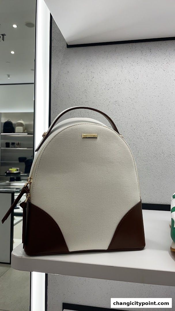 A stylish canvas and leather backpack displayed on a shelf in a retail store.