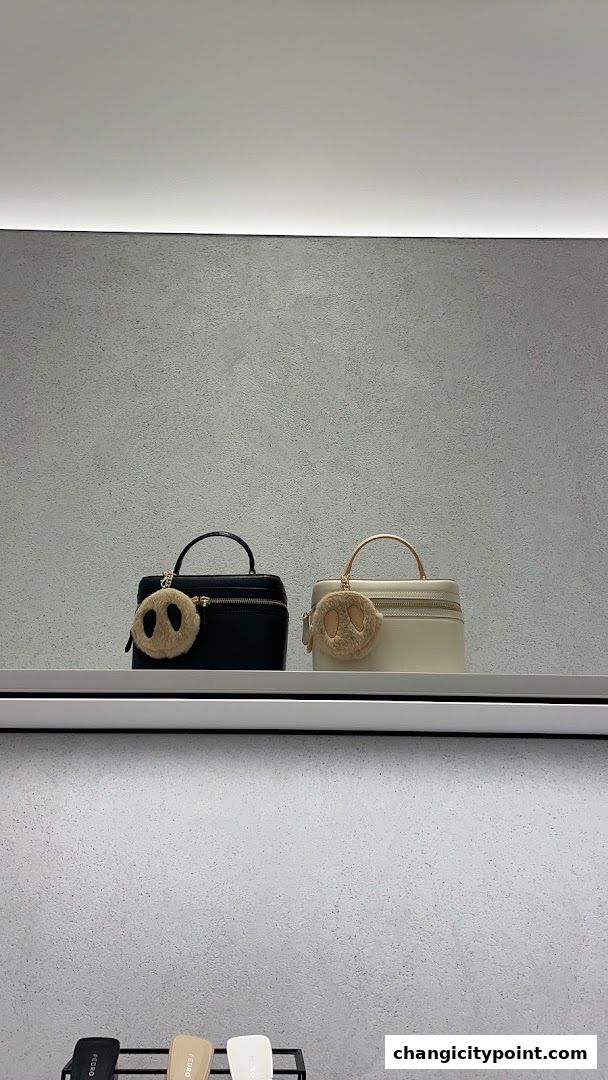 Two stylish handbags, one black and one cream, displayed with cute fuzzy charms.