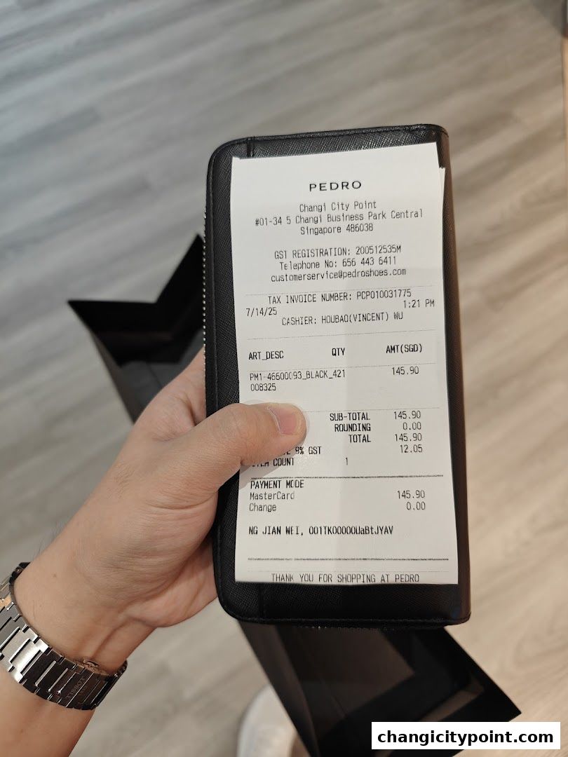 A hand holds a PEDRO receipt from Changi City Point, detailing a purchase.