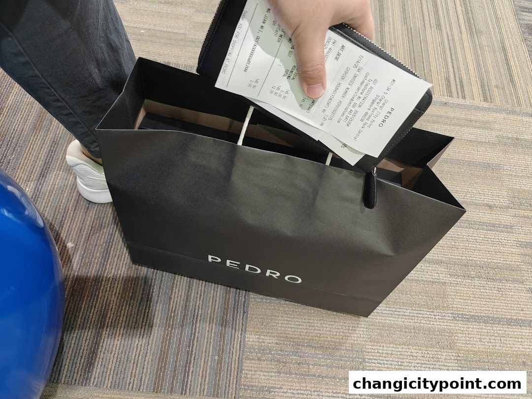 A person is placing a PEDRO shopping bag and a receipt into a wallet.