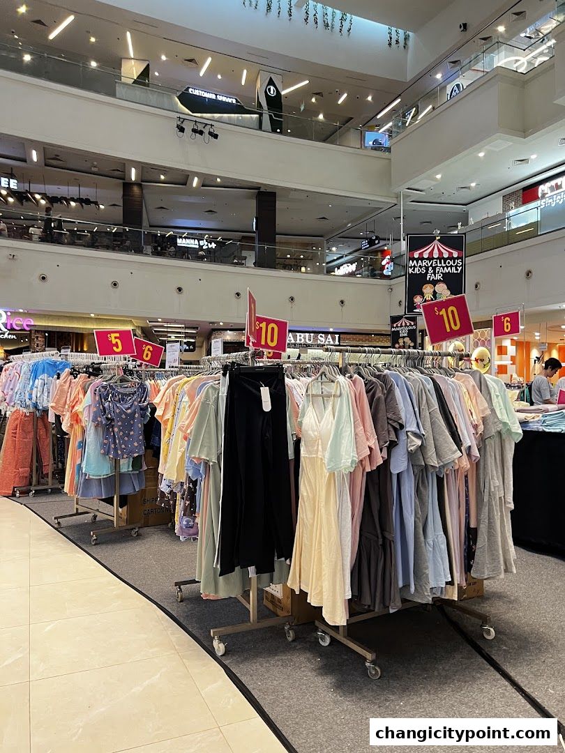A display of various clothing items on racks in a shopping mall.